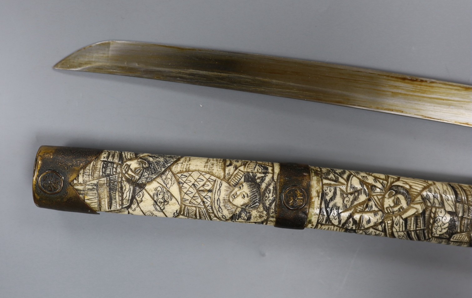 A late 19th century Japanese wakizashi sword, the blade 47.5cm, with sectional stag's horn scabbard and hilt carved with warriors and other figures, gilt metal mounted